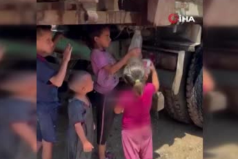 Gazzeli çocuklar kamyondan akan kirli suyu ellerindeki kaplara doldurdu